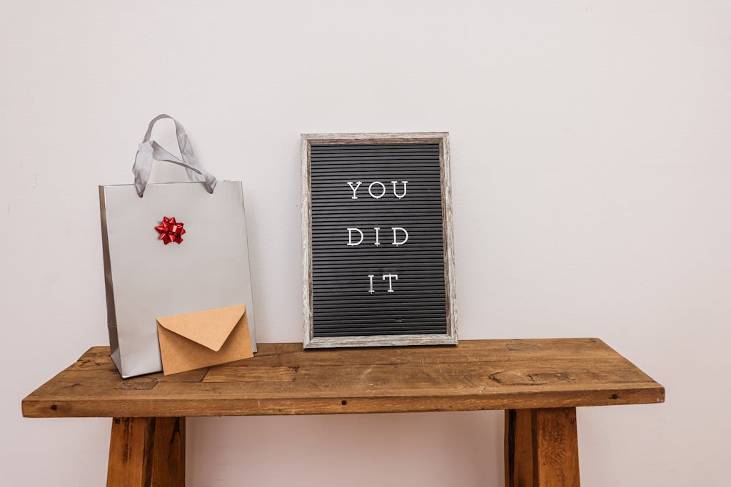 A Letter Board Beside a Present and Envelope on a Wooden Table